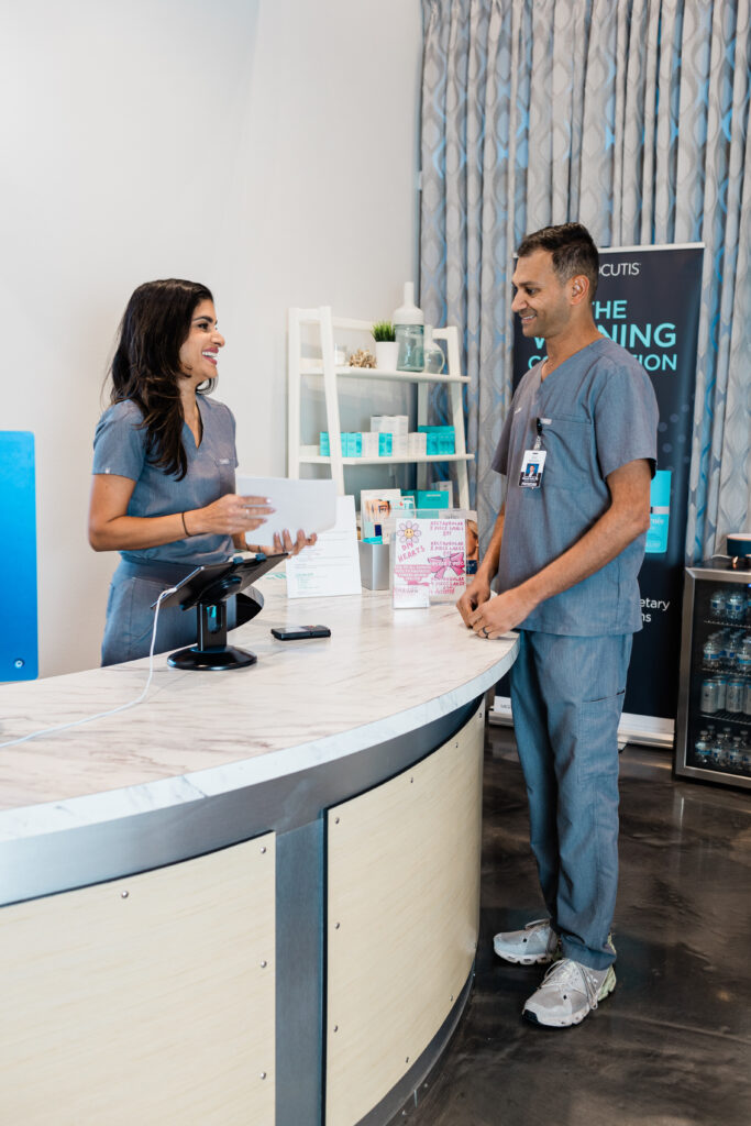 Saloni and DR.amin looking at each other and talking at the front desk