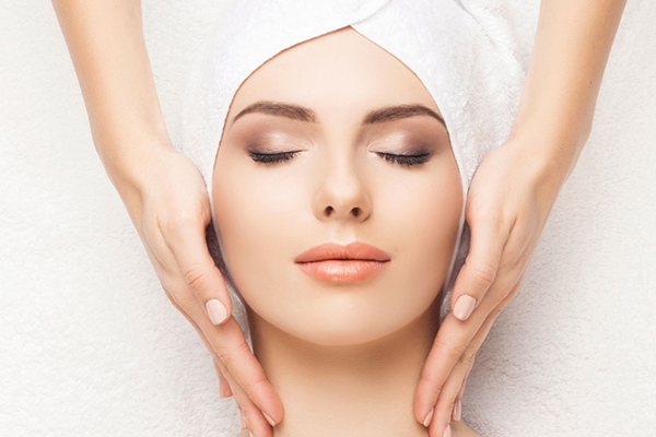 Woman enjoying face neck massage at spa