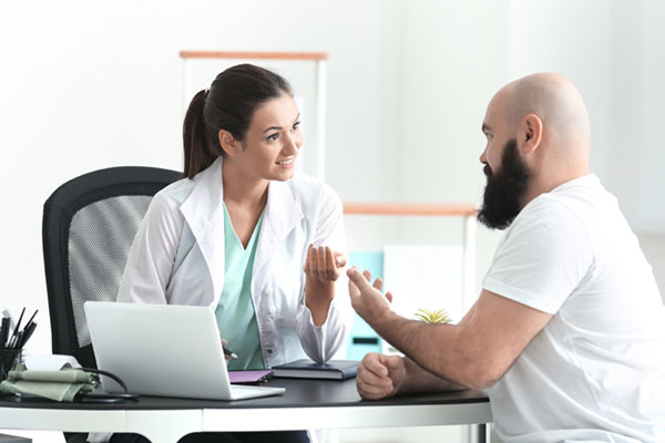 Young female doctor consulting overweight man in clinic